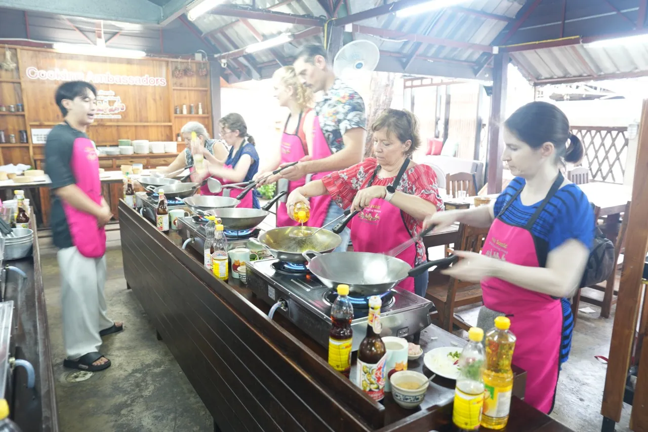 Travelers cooking Thai dishes at their own wok stations during Asia Scenic Old Town cooking class.