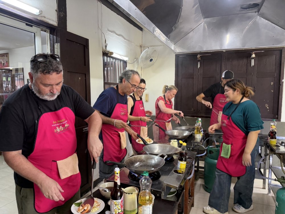 Guests learning hands-on wok cooking at Asia Scenic Thai Cooking School in Chiang Mai