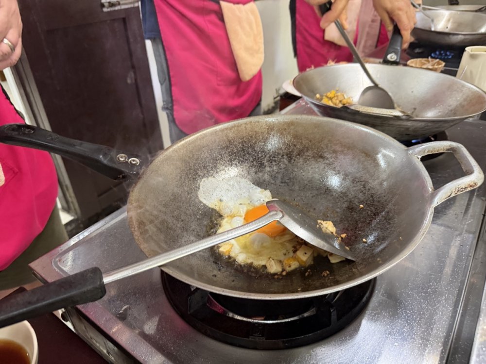 Learning authentic Thai wok cooking techniques step by step at Asia Scenic.