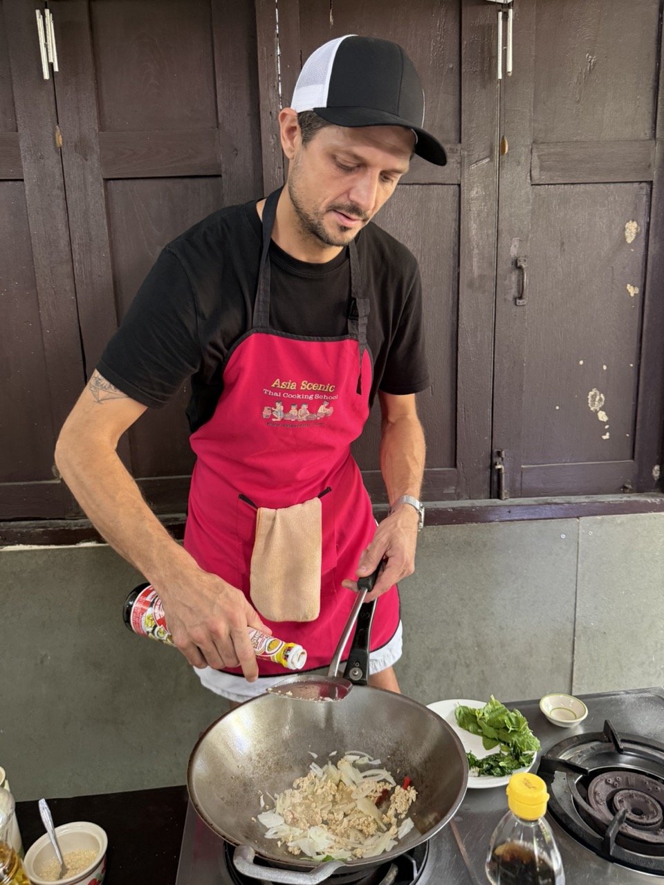 Guest seasoning and cooking his own Thai dish during a hands-on Chiang Mai cooking class.